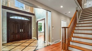 A spacious entryway with a large wooden double door, a tiled floor, and a wooden staircase. - Secluded Lux Mansion Pool Home With Amazing Views (Nassau)