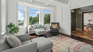 A spacious living room with a large window, a sofa, a chair, and a patterned rug. - Secluded Lux Mansion Pool Home With Amazing Views (Nassau)