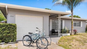A single-story house with a garage, a bicycle parked in front, and a palm tree.