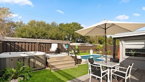 A backyard with a hot tub, a barbecue area, a pool, and a patio with outdoor furniture.