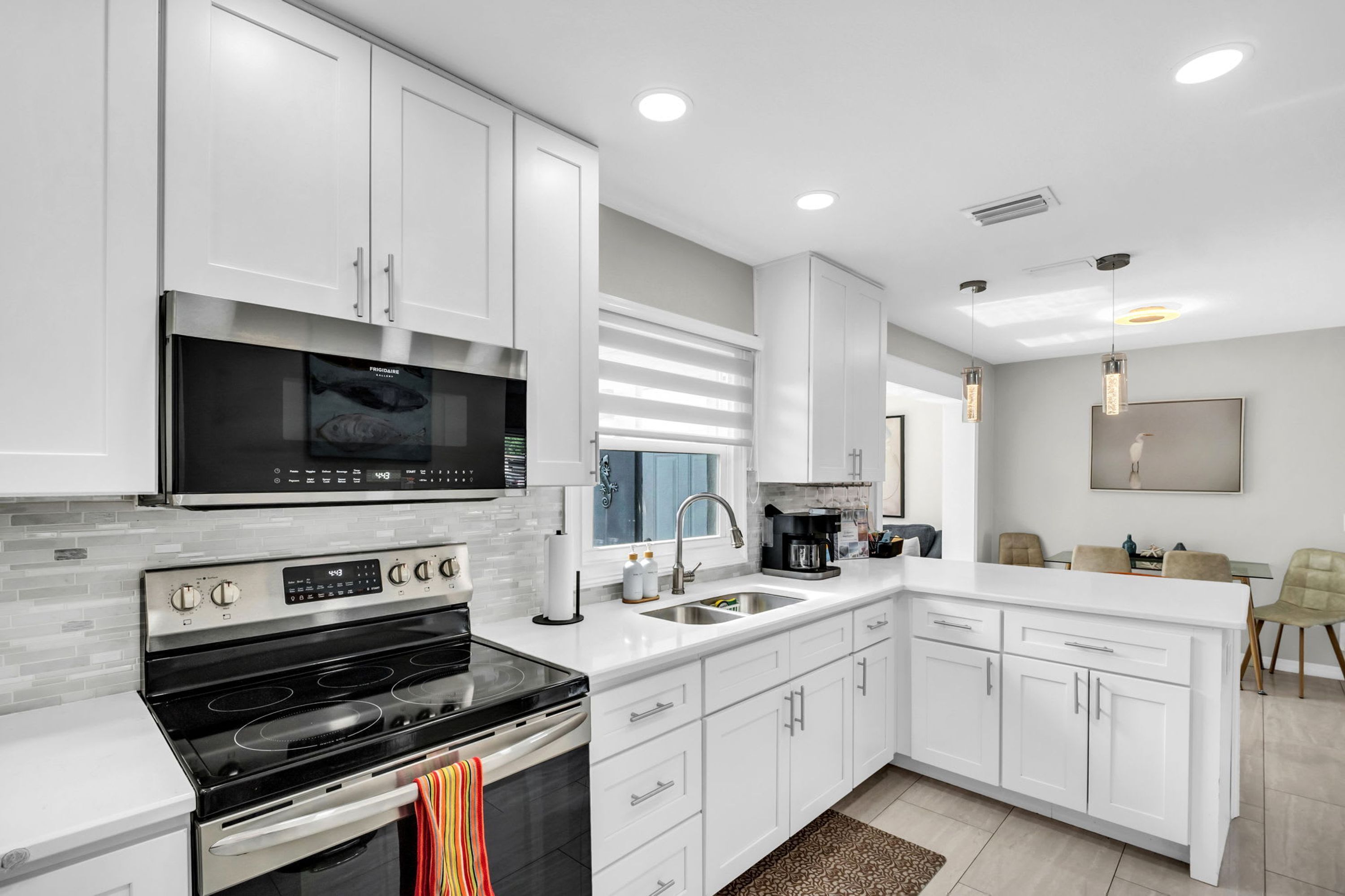 A modern kitchen with white cabinetry, a stainless steel range, and a built-in microwave.