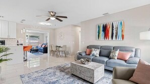 A modern living room with a grey sofa, a coffee table, and a dining area with chairs and a table.