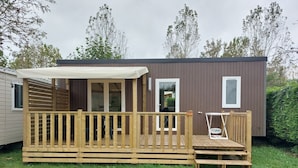Una terraza de madera con zona de estar cubierta, una mesa pequeña y un banco.