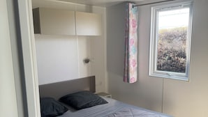 Un dormitorio con cama, ventana con vistas, mesita de noche y armario.