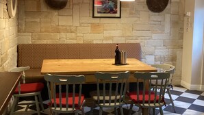A dining area with a wooden table, six chairs, a bench, and two pendant lights. - Ryans Roundstone Retreats Islandview (Roundstone)