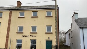 A building with the sign "Island View" on the facade, featuring multiple windows, a stone wall, and a green door. - Ryans Roundstone Retreats Islandview (Roundstone)