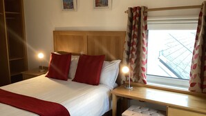 A neatly arranged bedroom with a bed, bedside tables, a desk, and a window with curtains. - Ryans Roundstone Retreats Islandview (Roundstone)