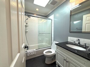 A modern bathroom with a glass-enclosed shower, a white toilet, and a vanity with a black countertop. - 3bd/2ba Remodeled Luxury Home + Steam Shower! (Concord)