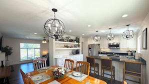 Una cocina moderna con armarios blancos, electrodomésticos de acero inoxidable e iluminación colgante.