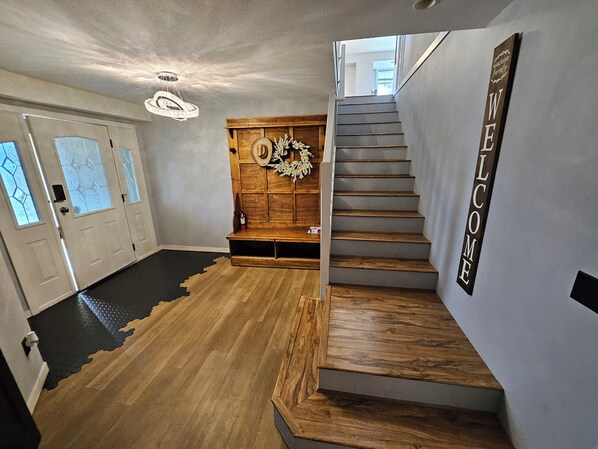Un interior moderno con un banco de madera, una escalera y un cartel que dice 'WELCOME'.