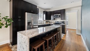 A modern kitchen with dark cabinets, stainless steel appliances, and a granite countertop.