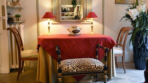 Un coin repas avec une table recouverte d’une nappe rouge, deux chaises dotées de coussins à motifs léopard et deux lampes rouges.