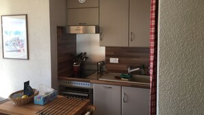 Una cocina compacta con horno Bosch, microondas integrado y extractor de acero inoxidable.