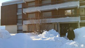 Un edificio de varios pisos con techo plano y balcones, sobre suelo cubierto de nieve.
