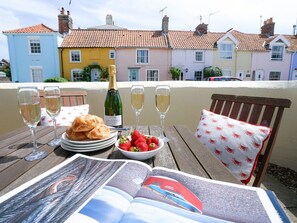 Une terrasse avec une table dressée pour un repas, comprenant des croissants, des fraises et des coupes à champagne.