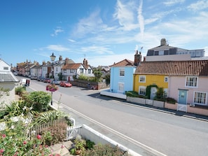 A street view with colorful houses, a clear sky, and a road with cars. - The Corner Cottage (Aldeburgh)