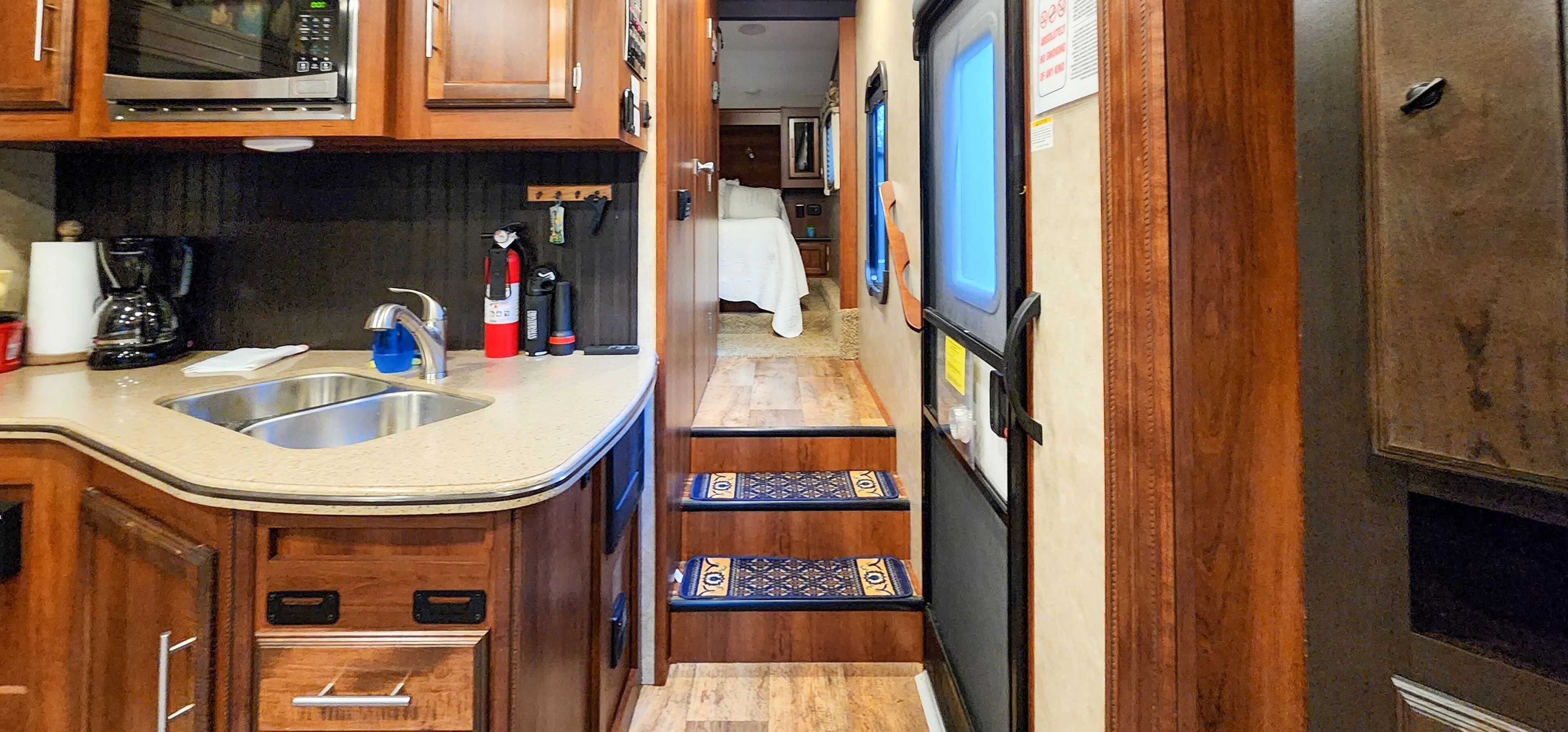 A compact kitchen with a microwave, sink, and stove. There are cabinets and a small countertop.