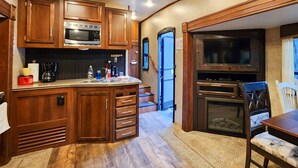 A compact kitchen with wooden cabinets, a microwave, and a built-in oven. - Bungalow+RV/10 acres/Stream/Sleeps6 (Ellijay)