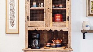A rustic wooden cabinet with shelves containing kitchen items, a coffee maker, and decorative teapots. - 1BR near St. Anthony — comfortable base for nurses and medical stays in OKC (Oklahoma City)