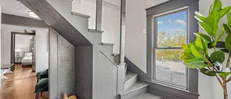 Un intérieur moderne avec un escalier, une plante en pot et une vue sur l’extérieur.