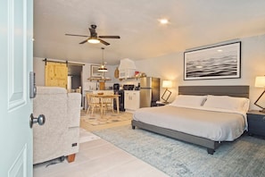 A bedroom with a bed, bedside table, lamp, and a painting on the wall.