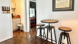 Una habitación con cocina, una mesa de comedor con taburetes y un periódico enmarcado en la pared.
