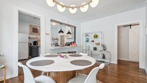 A modern kitchen with white cabinets, a central island, and a dining area with a round table and chairs.