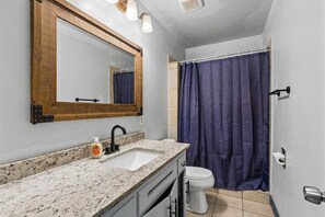 Un baño con lavamanos, espejo e inodoro.