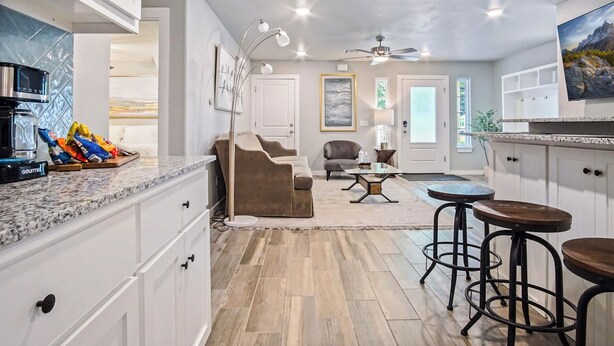 A modern kitchen with white cabinets, a granite countertop, and a coffee maker. There is a dining area with a round table and bar stools. - 5BR Bethany home, Sleeps 10 — hot tub, full kitchen, near Wiley Post & SNU. (Oklahoma)