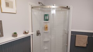 A modern bathroom with a glass-enclosed shower, white tiled walls, and a beige towel hanging on a rack. - Cozy Apartment in the Heart of Downtown Geneva (Geneva)