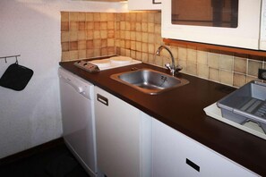 A compact kitchen with a dishwasher, a sink, and a microwave.