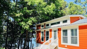 A two-story house with a white staircase and orange siding, surrounded by trees.