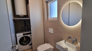 Ein kleines Badezimmer mit Waschmaschine, Toilette und Waschbecken.
