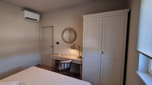 Ein Schlafzimmer mit Bett, Schreibtisch, Stuhl, Kleiderschrank und einer Klimaanlage.