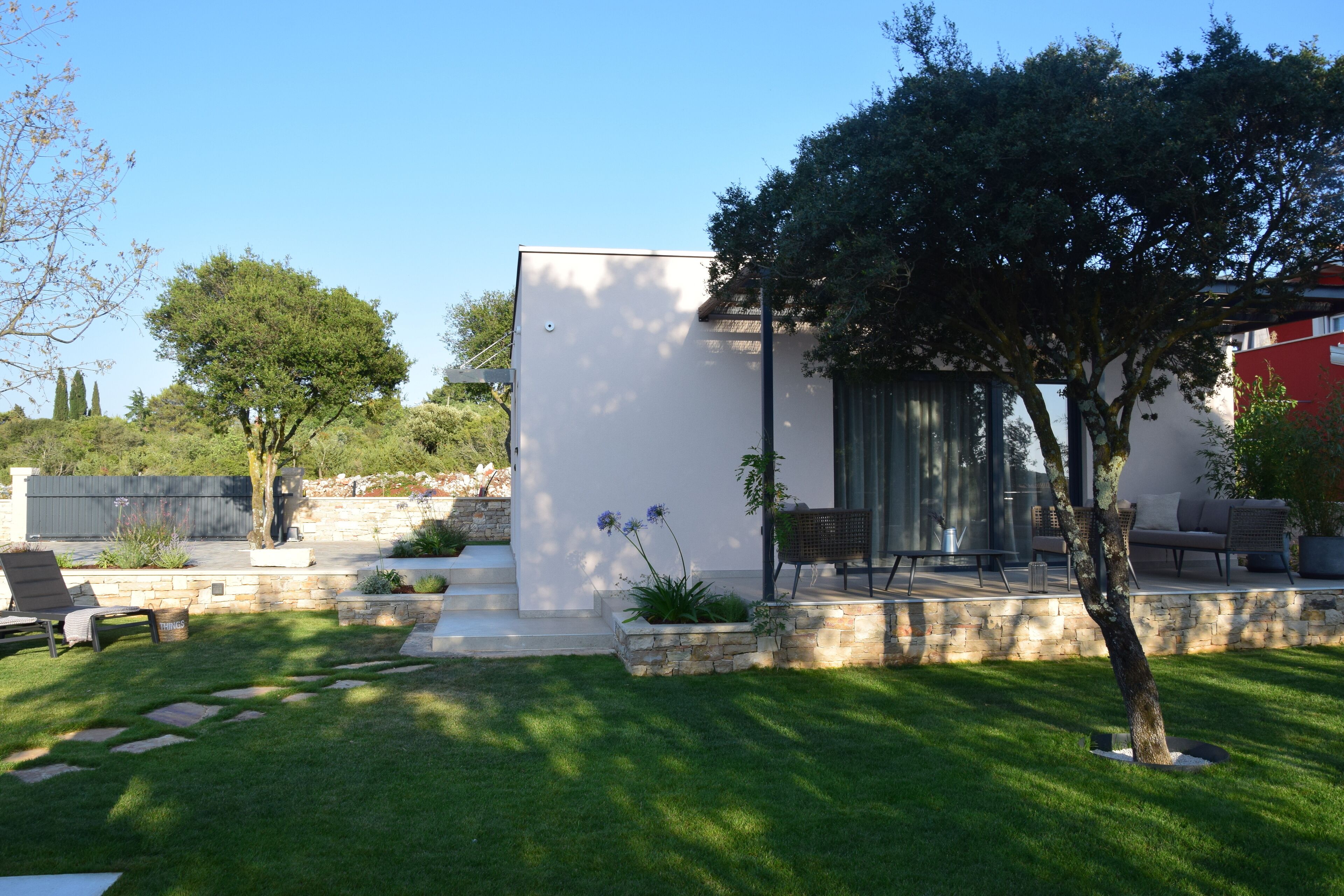 Une maison moderne dotée d’un patio, de marches en pierre et d’une pelouse.