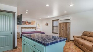 A bedroom with a bed, a nightstand, a window with blinds, and a wooden wardrobe.