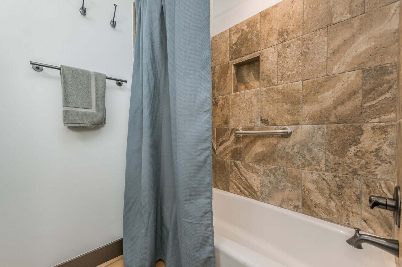 A bathroom with a bathtub, a towel rack, and a shower curtain.