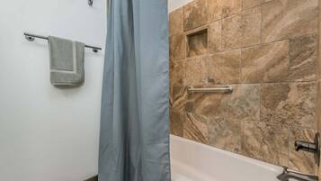 A bathroom with a bathtub, a towel rack, and a shower curtain.