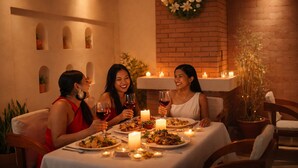A dining area with a brick wall, a hanging wreath, candles, and a table set for three people. - Mahafaly Hotel & Resort (Antsirabe)