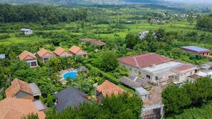 A residential area with multiple houses, a swimming pool, and lush greenery. - Mahafaly Hotel & Resort (Antsirabe)