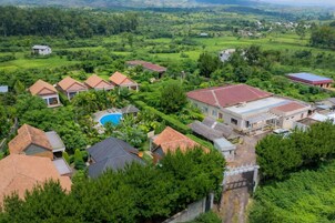 Un barrio residencial con varias casas, una piscina y abundante vegetación.
