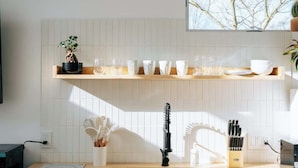 A modern kitchen with white cabinetry, a wooden countertop, a built-in sink, and a window above the countertop.
