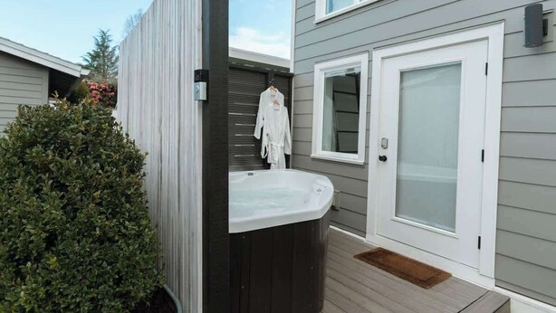 A spa area with a hot tub, a wooden deck, and a white door with frosted glass.