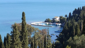 A coastal view with a marina, boats, and a building with a sloped roof. - Villa Bacchus (Corfu)