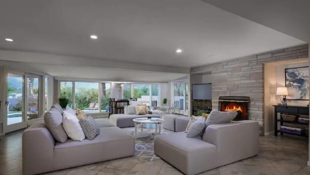 A spacious living room with a fireplace, comfortable seating, and large windows offering a view of the outdoors. - Wall Street Journal Featured-6 bath Lux Resort Home (Paradise Valley)