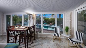 A sunroom with a pool view, a dining table with chairs, and striped chairs. - Wall Street Journal Featured-6 bath Lux Resort Home (Paradise Valley)