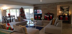 Ein Wohnzimmer mit Kamin, Weihnachtstannen und Fernseher.