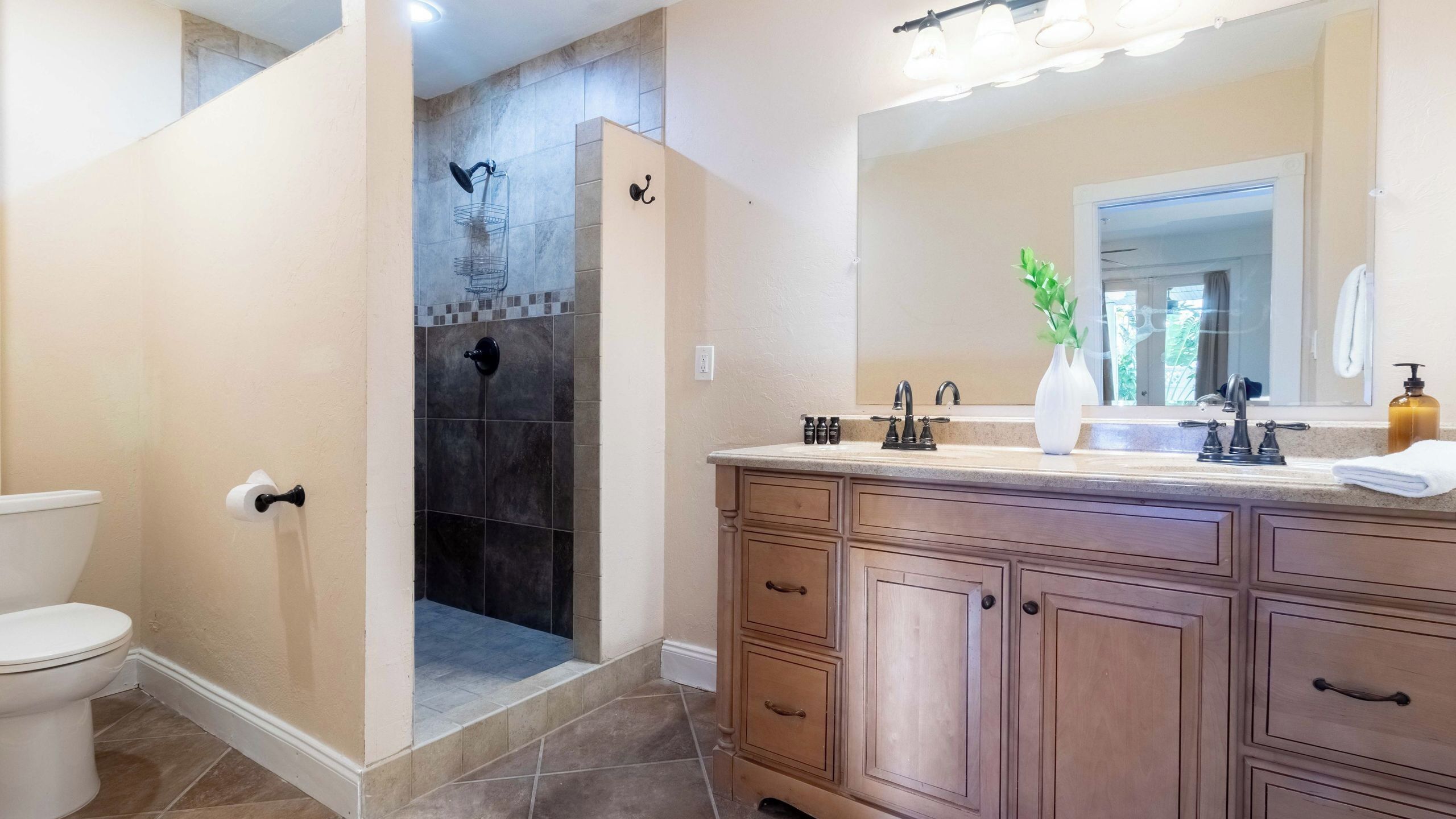 Une salle de bain comprenant une douche, des toilettes, un meuble-lavabo avec des tiroirs, un miroir et un lavabo.