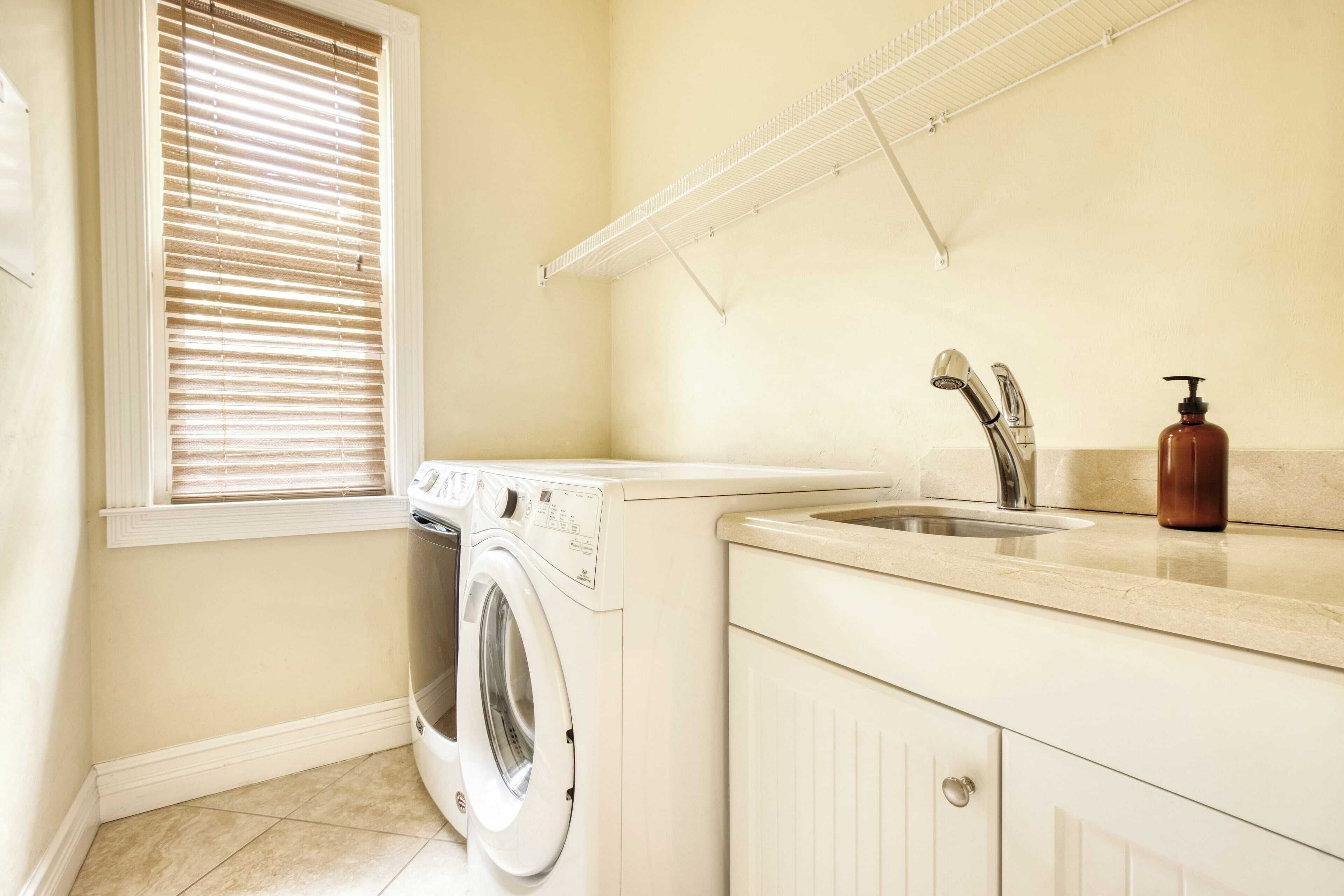A laundry area with a washing machine, a sink, and a drying rack.