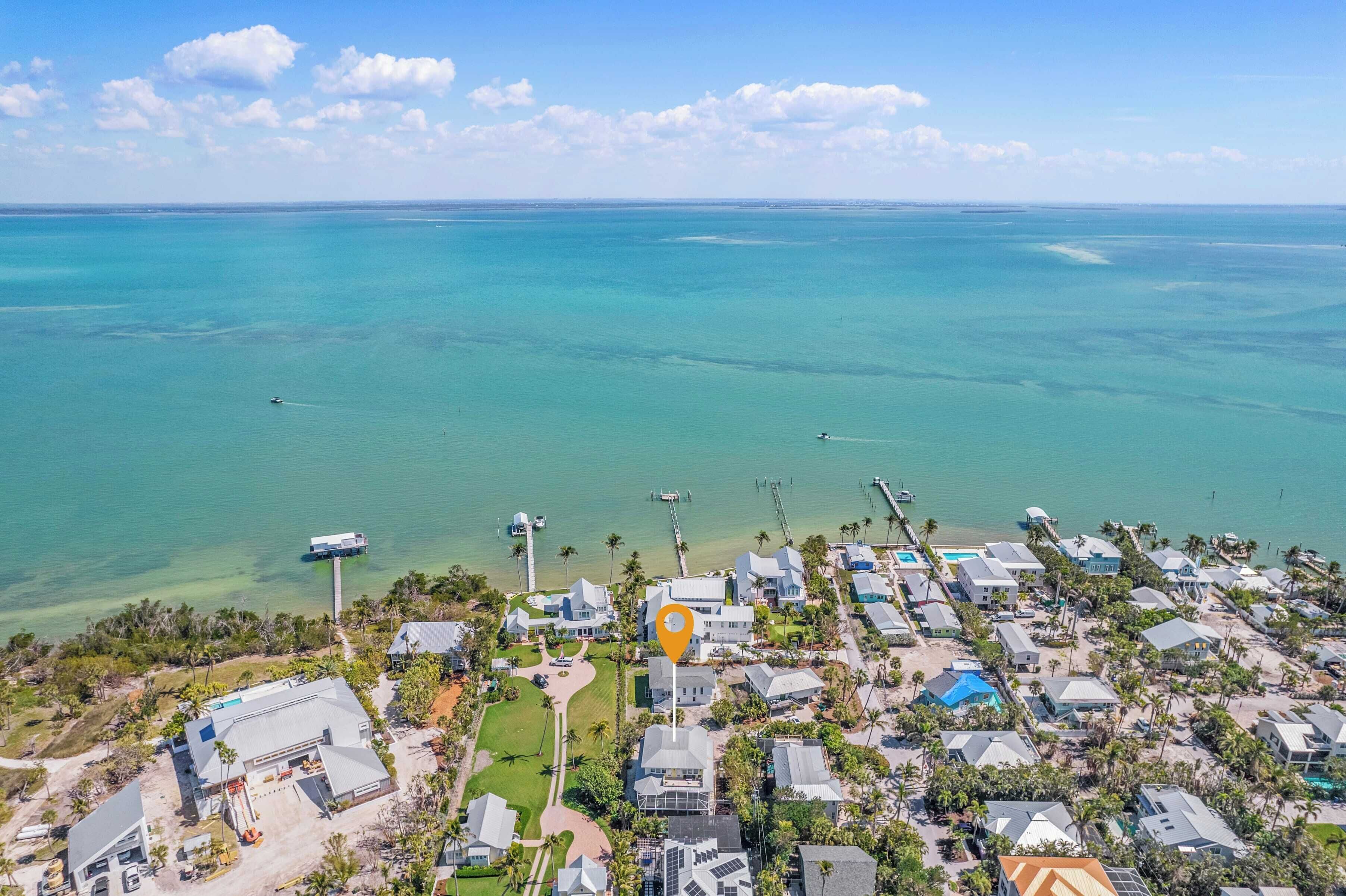 Vista aérea de una zona residencial costera con casas, un muelle y una vista despejada del océano.